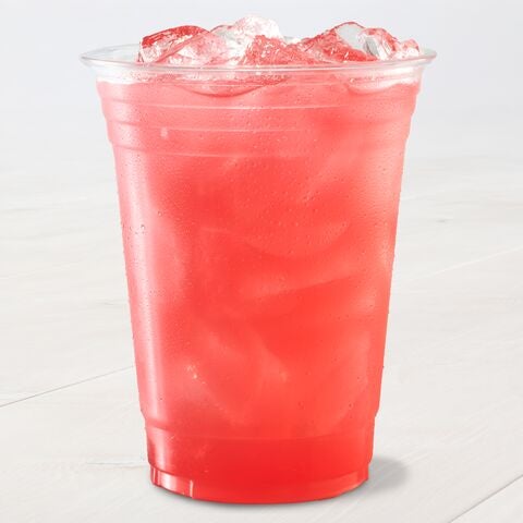 A clear plastic cup filled with a vibrant red, iced beverage sits on a light surface. The drink appears refreshing.
