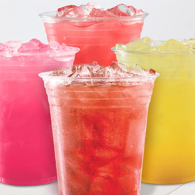 Four plastic cups filled with iced drinks in shades of pink, red, and yellow, arranged closely. Refreshing and vibrant, conveying a summery vibe.