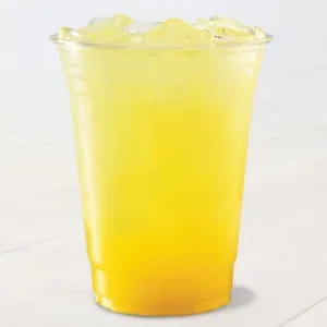 A clear plastic cup filled with a bright yellow, iced beverage sits on a light surface. The drink appears refreshing.