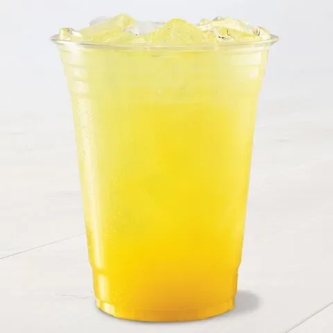 A clear plastic cup filled with a bright yellow, iced beverage sits on a light surface. The drink appears refreshing.